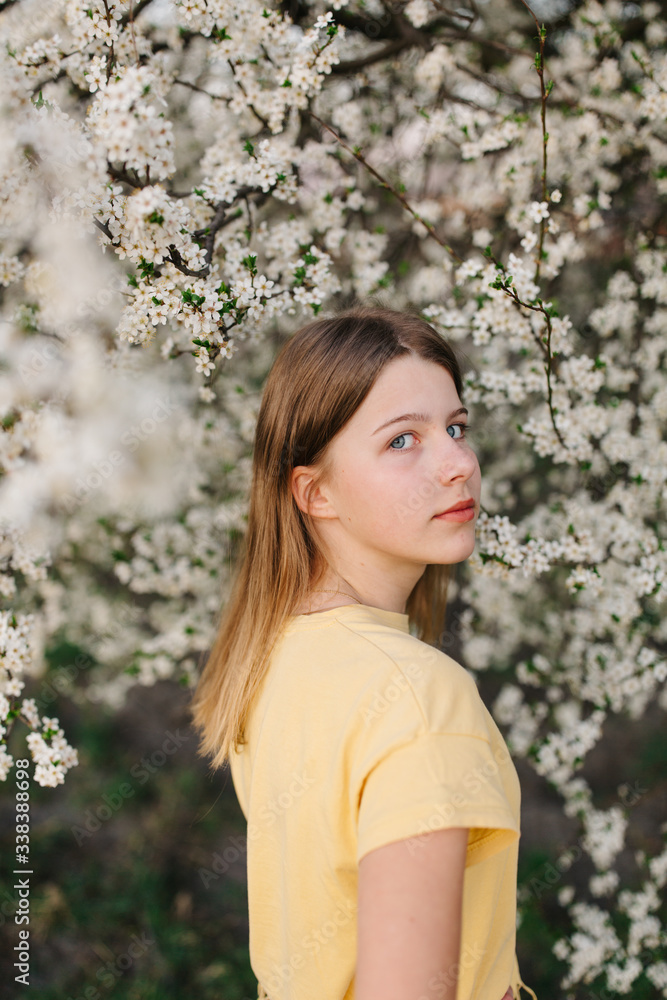 portrait of sad young woman in protective medical face mask with flowers near blooming tree in spring time. Coronavirus protection. epidemic of coronavirus. the aroma a tree in the garden on a spring portrait of sad young woman in protective medical face mask with flowers near blooming tree in spring time. Coronavirus protection. epidemic of coronavirus. the aroma a tree in the garden on a spring
