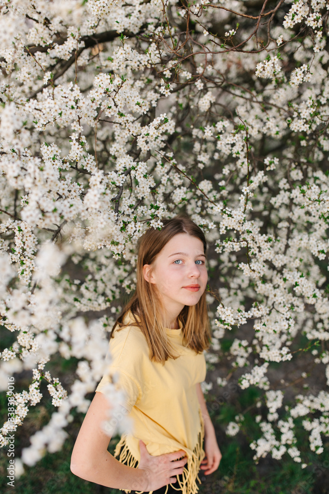 portrait of sad young woman in protective medical face mask with flowers near blooming tree in spring time. Coronavirus protection. epidemic of coronavirus. the aroma a tree in the garden on a spring portrait of sad young woman in protective medical face mask with flowers near blooming tree in spring time. Coronavirus protection. epidemic of coronavirus. the aroma a tree in the garden on a spring
