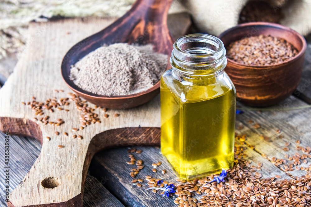 Flaxseed oil in a bottle near flaxseed on a wooden table. Flaxseed oil in a bottle near flaxseed on a wooden table.