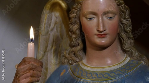 close up of a statue of an angel holding a burning candle in his hand photo