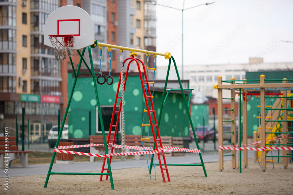 Playground is closed for quarantine, the playground is blocked by a red warning tape, children cannot play on the street Playground is closed for quarantine, the playground is blocked by a red warning tape, children cannot play on the street