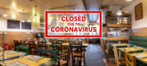 Closed due to coronavirus sign on defocused empty restaurant room