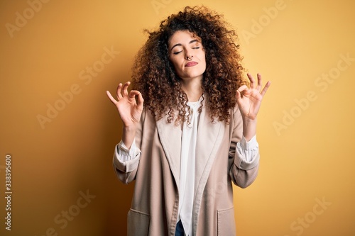 Young beautiful brunette woman with curly hair and piercing wearing casual t-shirt and diadem relax and smiling with eyes closed doing meditation gesture with fingers. Yoga concept.