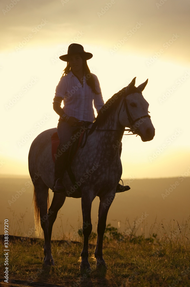 Female horseback rider and horse ride to overlook at Lewa Wildlife Conservancy in North Kenya, Africa at sunset Female horseback rider and horse ride to overlook at Lewa Wildlife Conservancy in North Kenya, Africa at sunset