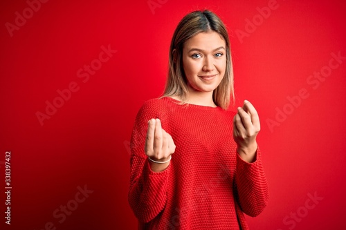 Obraz na plátně Young beautiful blonde woman wearing casual sweater over red isolated background