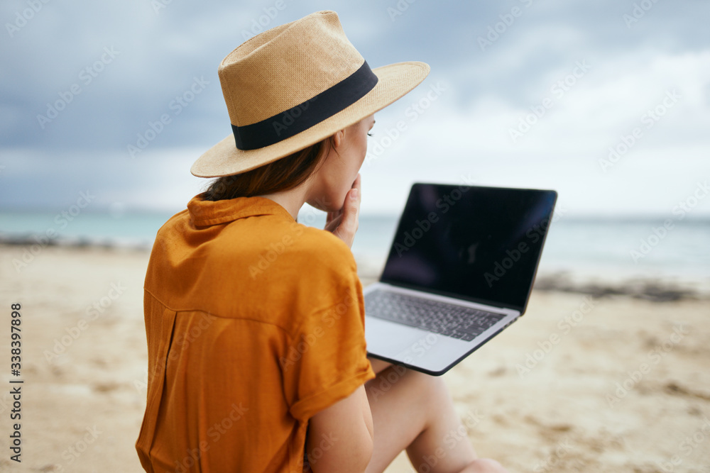 young woman with laptop on the beach