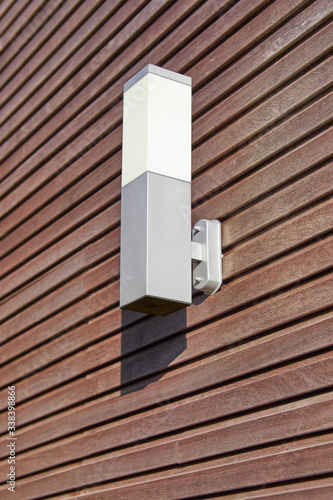 Exterior lamp against a padouk wooden wall photo