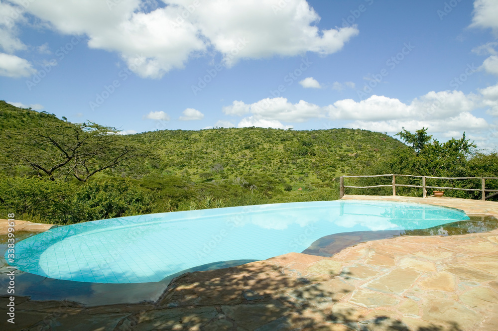 Swimming pool with turquoise water surrounded by the hills of North Kenya, Africa at the Lewa Wildlife Conservancy