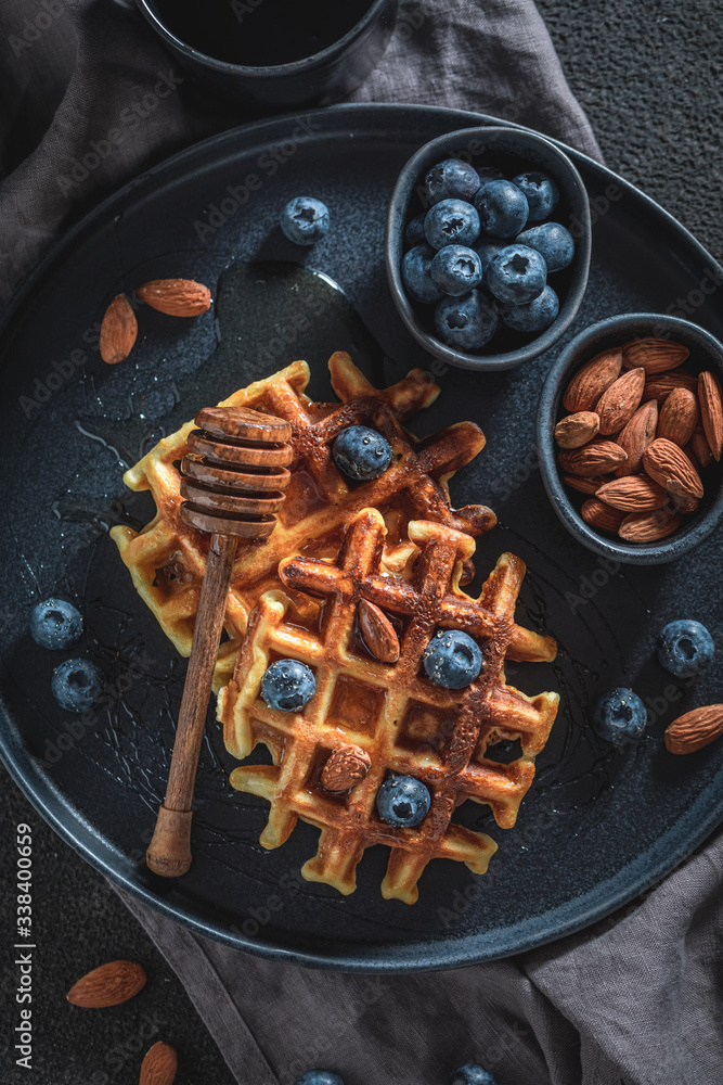 Fototapeta premium Tasty waffles with honey, blueberries and almont
