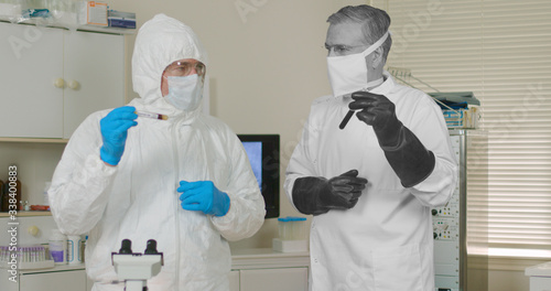 Schilderij op canvas Scene with two medical research scientists one from the present and one from the past both in full PPE garb dealing with pandemics