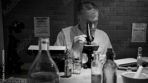 In black and white a scientist during the 1918 influenza pandemic working in his private laboratory searching for a cure to the Spanish Flu.