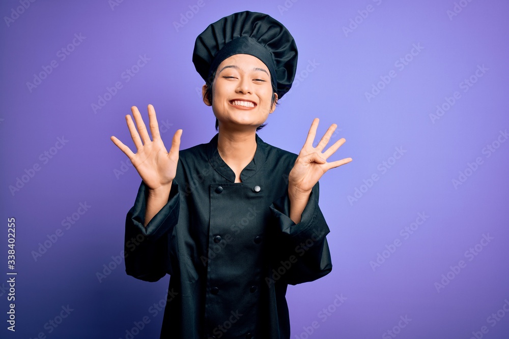 Young beautiful chinese chef woman wearing cooker uniform and hat over purple background showing and pointing up with fingers number nine while smiling confident and happy. Young beautiful chinese chef woman wearing cooker uniform and hat over purple background showing and pointing up with fingers number nine while smiling confident and happy.