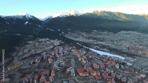 Flying over village on sunny morning with snowy mountains on the horizon photo