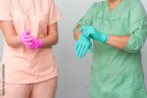 Two female beauticians wearing gloves ready before procedures  medical employees  close up.