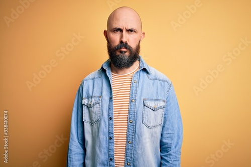 Handsome bald man with beard wearing casual denim jacket and striped t-shirt depressed and worry for distress, crying angry and afraid. Sad expression.