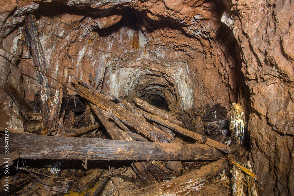 Underground abandoned bauxite ore mine tunnel with collapsed wooden timbering Underground abandoned bauxite ore mine tunnel with collapsed wooden timbering