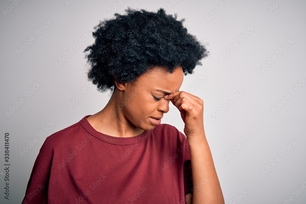 Young beautiful African American afro woman with curly hair wearing casual t-shirt standing tired rubbing nose and eyes feeling fatigue and headache. Stress and frustration concept. Young beautiful African American afro woman with curly hair wearing casual t-shirt standing tired rubbing nose and eyes feeling fatigue and headache. Stress and frustration concept.