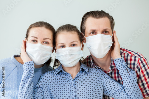 Family in protective medical masks. Mother, father, daughter protect themselves from the virus at home. Coronavirus.
