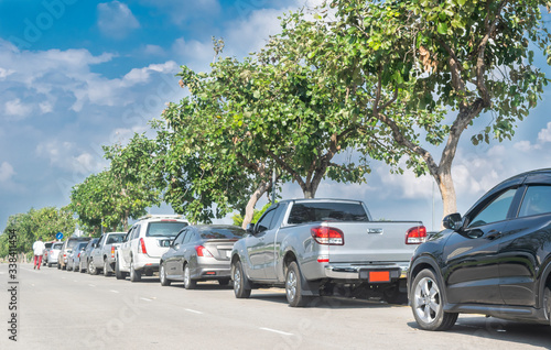 Cars parked in a row on street side under trees. business cars parking on road side © merrymuuu