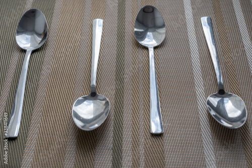 metal spoons are arranged on brown cloth decorated with thin brown stripes