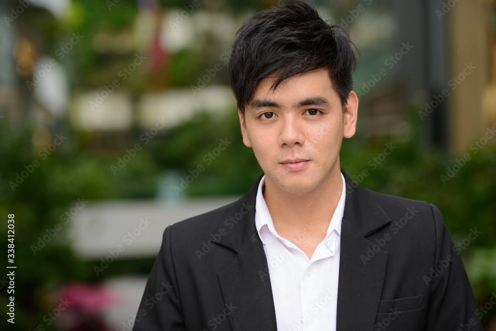 Face of young handsome Asian businessman at the park Face of young handsome Asian businessman at the park