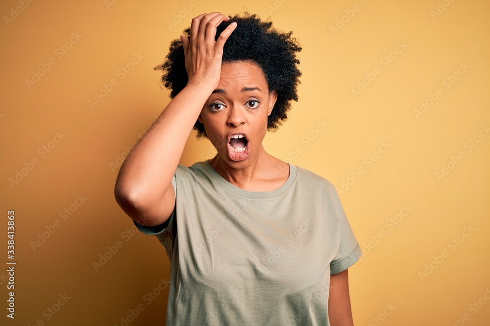 Young beautiful African American afro woman with curly hair wearing casual t-shirt surprised with hand on head for mistake, remember error. Forgot, bad memory concept. Young beautiful African American afro woman with curly hair wearing casual t-shirt surprised with hand on head for mistake, remember error. Forgot, bad memory concept.