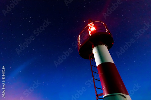 red lighthouse on the background of stars