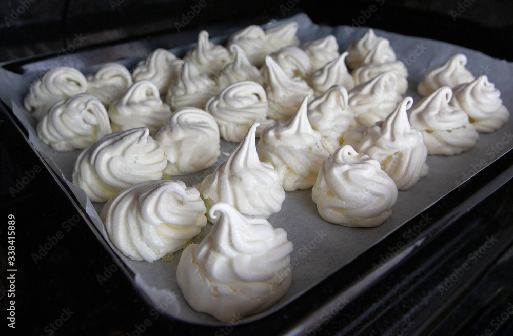 meringues cooked in the oven on a black baking tray
