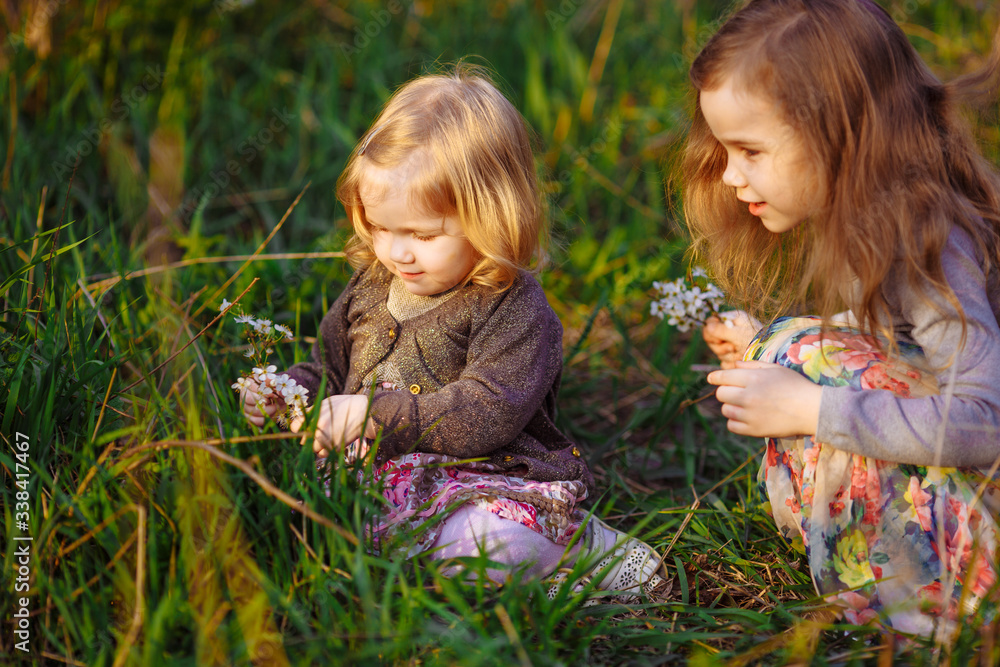 little girls sitting in grass with blossoming twig little girls sitting in grass with blossoming twig