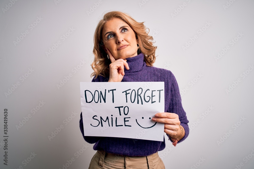 Middle age beautiful blonde woman holding banner funny positive message serious face thinking about question, very confused idea Middle age beautiful blonde woman holding banner funny positive message serious face thinking about question, very confused idea