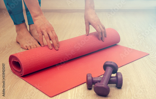 Girl rolls pink fitness mat at home