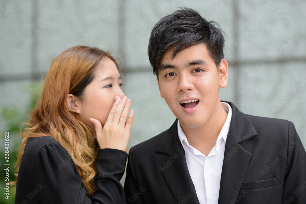 Young Asian business couple whispering together in the city Young Asian business couple whispering together in the city