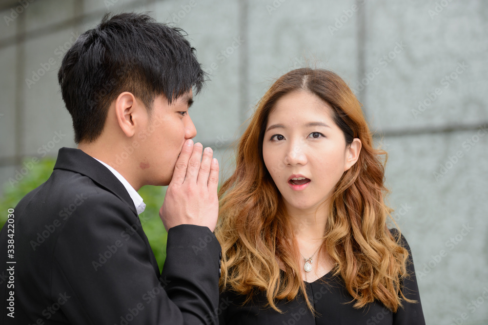 Young Asian business couple whispering together in the city Young Asian business couple whispering together in the city