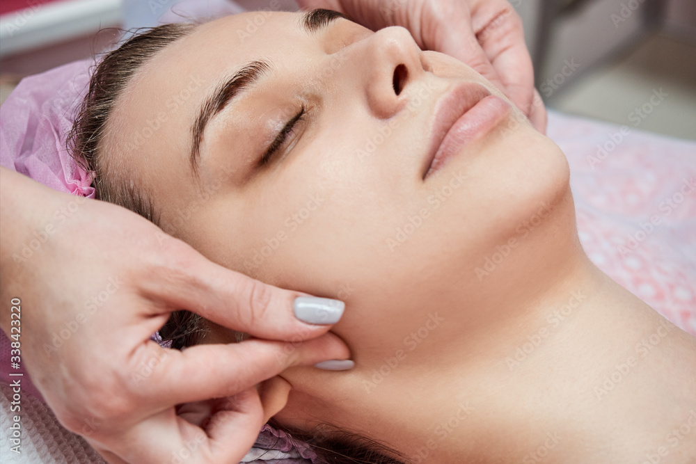 Beautician does facial massage. Anti-aging treatment in a beauty salon.