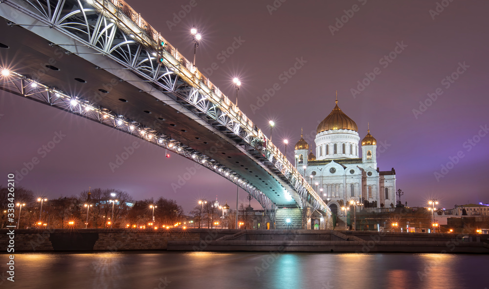 The Cathedral of Christ the Saviour or Savior and Patriarchal pedestrian bridge with night illumination in the evening in Moscow, Russia. Russian Orthodox church on the Moskva river
