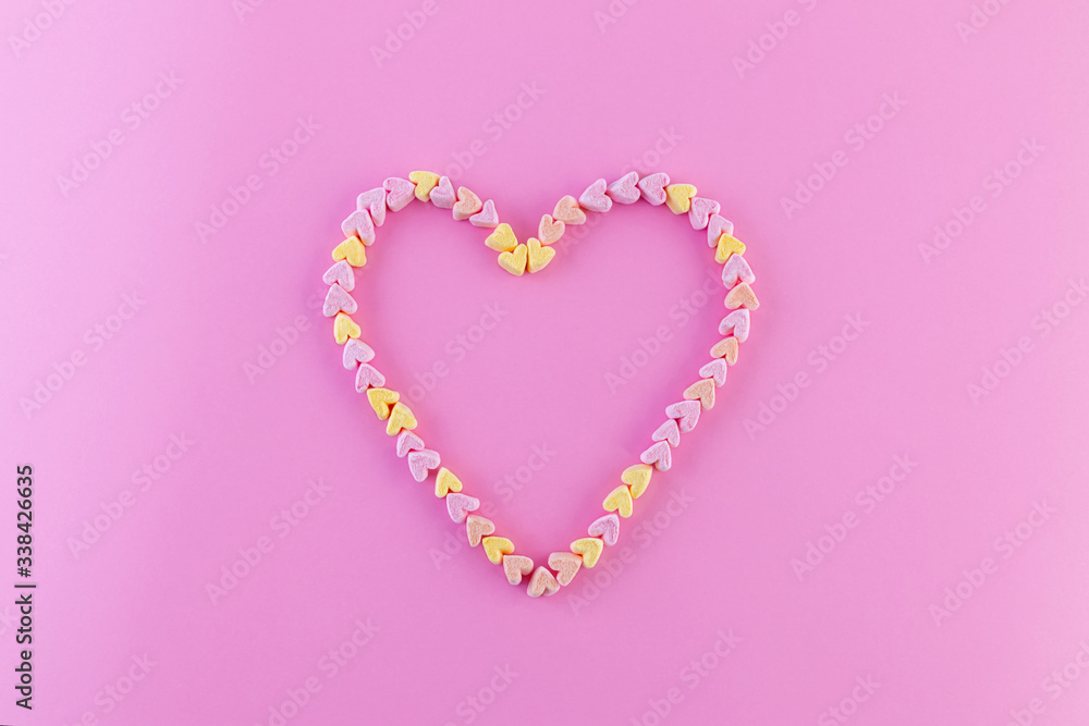 Creative mock-up of pastel marshmallows in the shape of a heart on a bright pink background. The concept of love, happiness in detail. Flat lay. Copy space