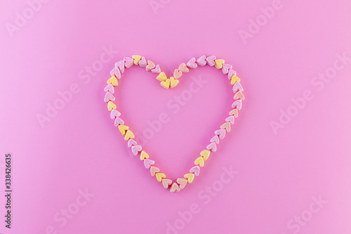 Creative mock-up of pastel marshmallows in the shape of a heart on a bright pink background. The concept of love, happiness in detail. Flat lay. Copy space