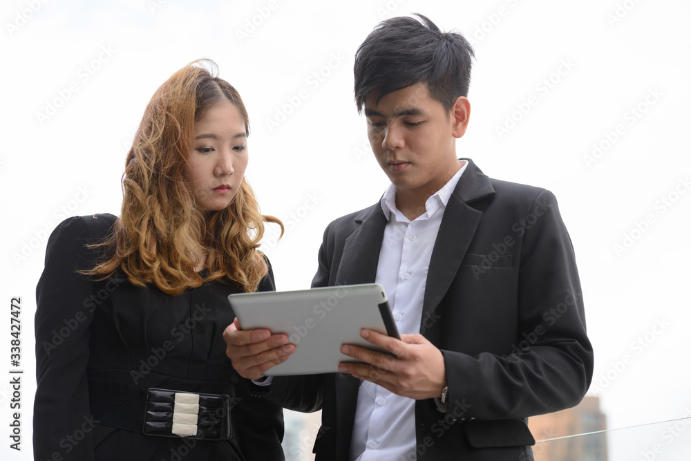 Young Asian business couple using digital tablet together in the city Young Asian business couple using digital tablet together in the city