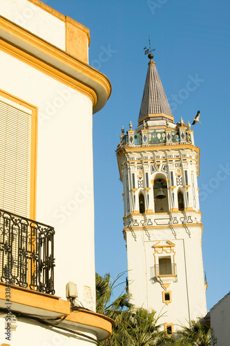 Storks nest on white cathedral tower with beautiful sunlight in village of Southern Spain off highway A49 west of Sevilla photo