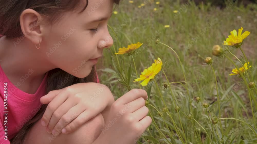 A little girl is looking at a yellow daisy. A little girl is looking at a yellow daisy.