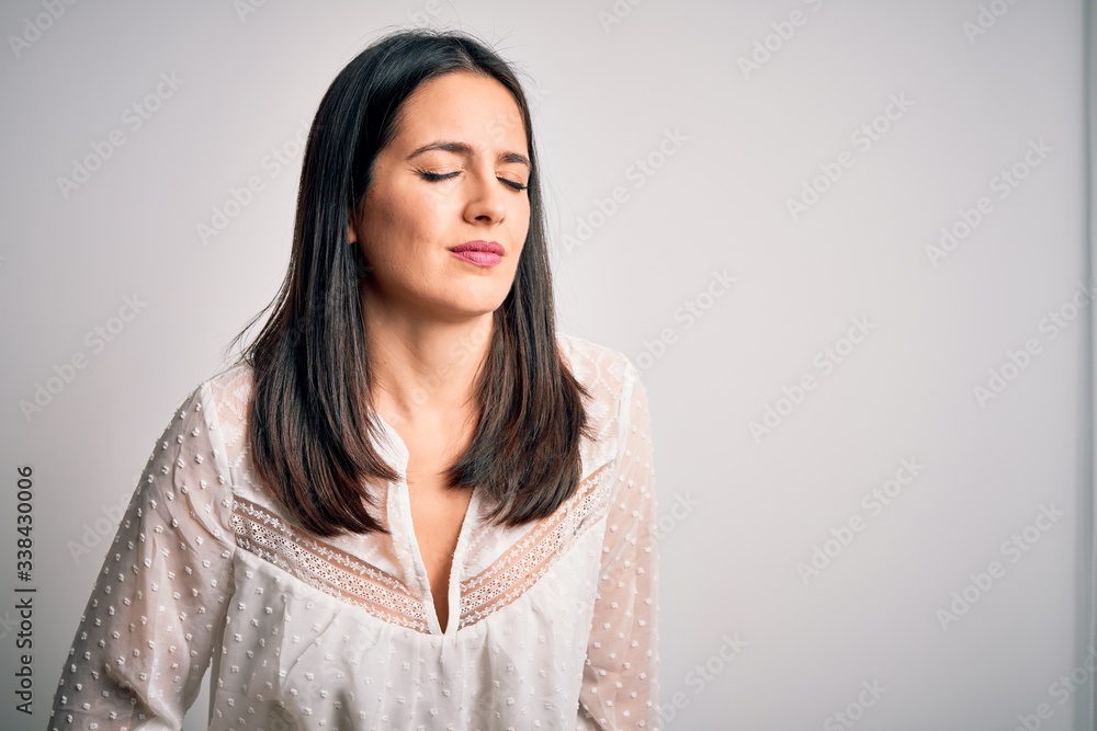 Young brunette woman with blue eyes wearing casual t-shirt over isolated white background with hand on stomach because indigestion, painful illness feeling unwell. Ache concept. Young brunette woman with blue eyes wearing casual t-shirt over isolated white background with hand on stomach because indigestion, painful illness feeling unwell. Ache concept.