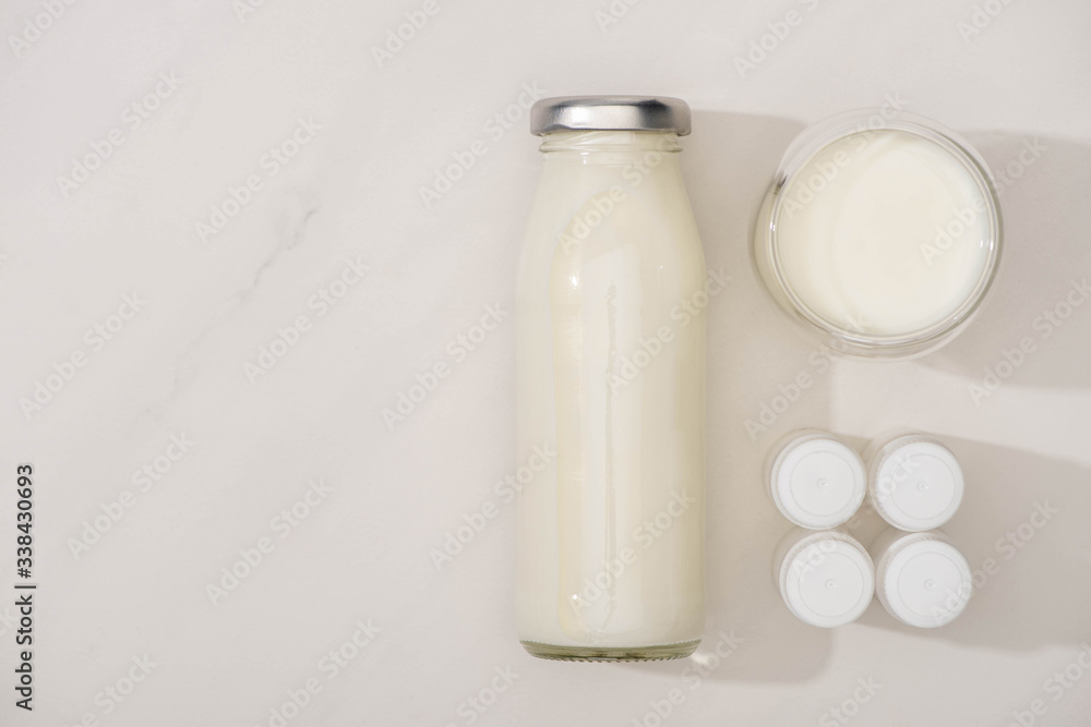 Top view of bottle and glass of homemade yogurt near containers with starter cultures on white background Top view of bottle and glass of homemade yogurt near containers with starter cultures on white background
