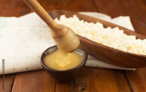 Cottage cheese in clay bowl and honey on wood table background. Dairy products and honey with copy space