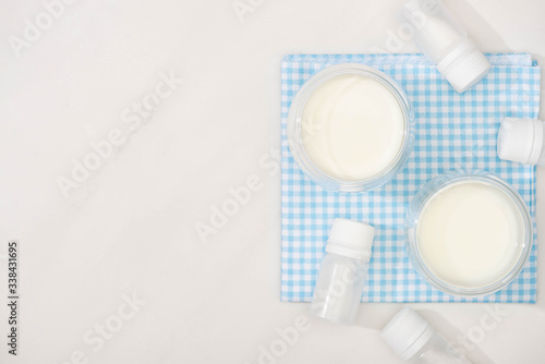 Top view of glasses of homemade yogurt and containers with starter cultures on cloth on white background
