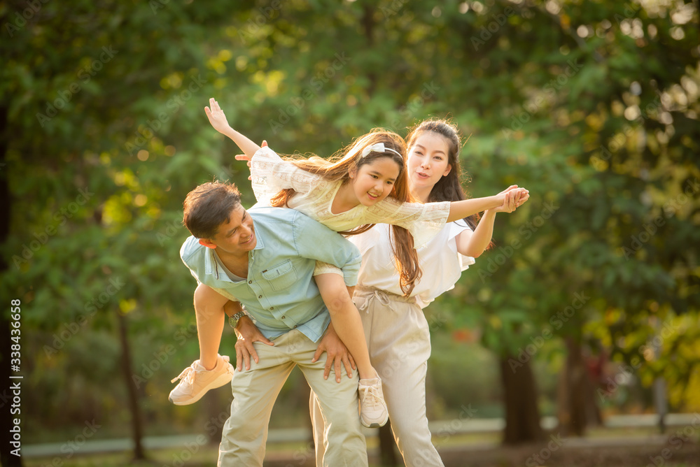 Obraz premium Happy family playing on the grass in the park at sunset. The concept of a happy family.