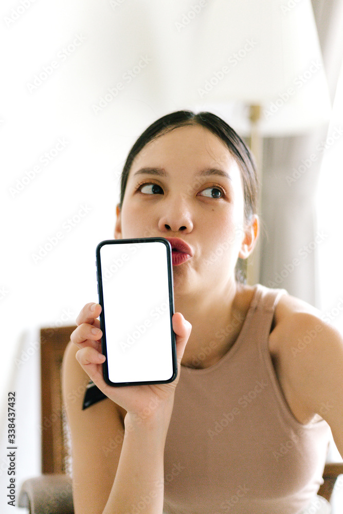 Asian cute woman is showing white blank smartphone screen on home studio background Asian cute woman is showing white blank smartphone screen on home studio background