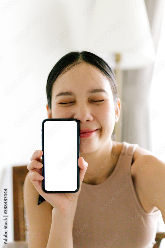 Asian cute woman is showing white blank smartphone screen on home studio background Asian cute woman is showing white blank smartphone screen on home studio background