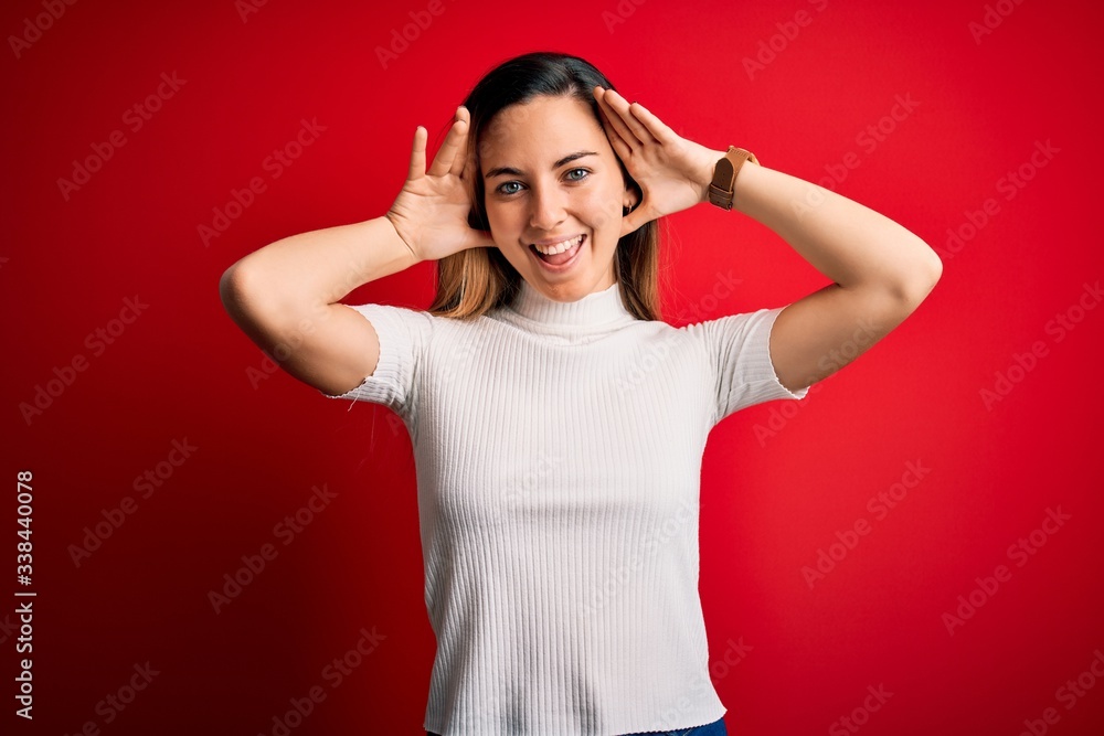 Beautiful blonde woman with blue eyes wearing casual white t-shirt over red background Smiling cheerful playing peek a boo with hands showing face. Surprised and exited Beautiful blonde woman with blue eyes wearing casual white t-shirt over red background Smiling cheerful playing peek a boo with hands showing face. Surprised and exited