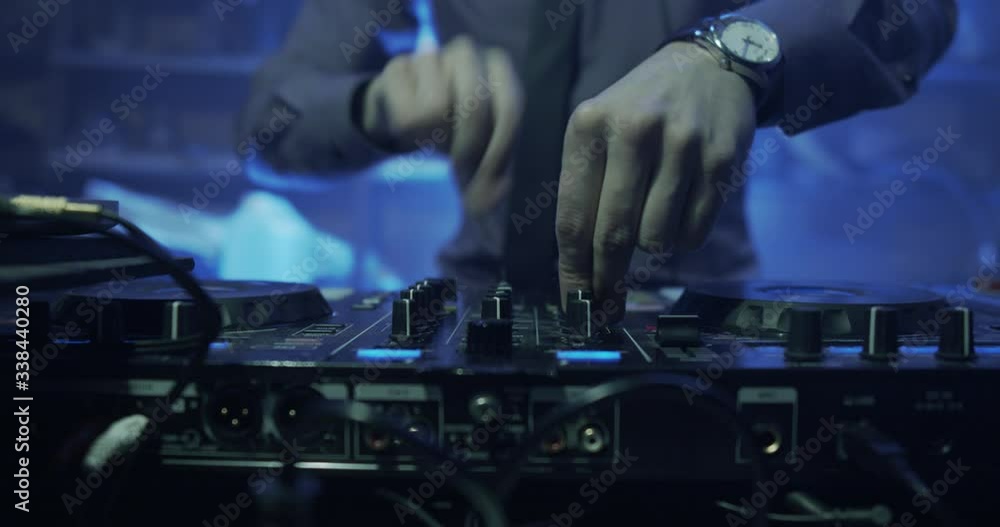 DJ plays live set and mixing music on turntable console at stage in the night club. Disc Jokey Hands on a sound mixer station at club party. DJ mixer controller panel for playing music and partying. DJ plays live set and mixing music on turntable console at stage in the night club. Disc Jokey Hands on a sound mixer station at club party. DJ mixer controller panel for playing music and partying.
