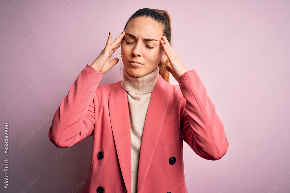 Young beautiful blonde businesswoman with blue eyes wearing elegant pink jacket suffering from headache desperate and stressed because pain and migraine. Hands on head. Young beautiful blonde businesswoman with blue eyes wearing elegant pink jacket suffering from headache desperate and stressed because pain and migraine. Hands on head.